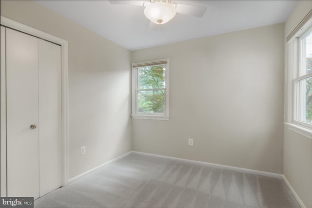 unfurnished bedroom featuring multiple windows, light colored carpet, and baseboards