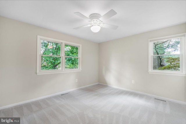 unfurnished room with light colored carpet, baseboards, and a ceiling fan