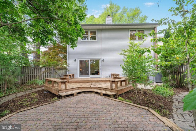 back of property featuring fence, a chimney, and a deck