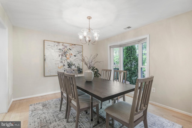 dining room with a chandelier, light wood-style floors, and baseboards