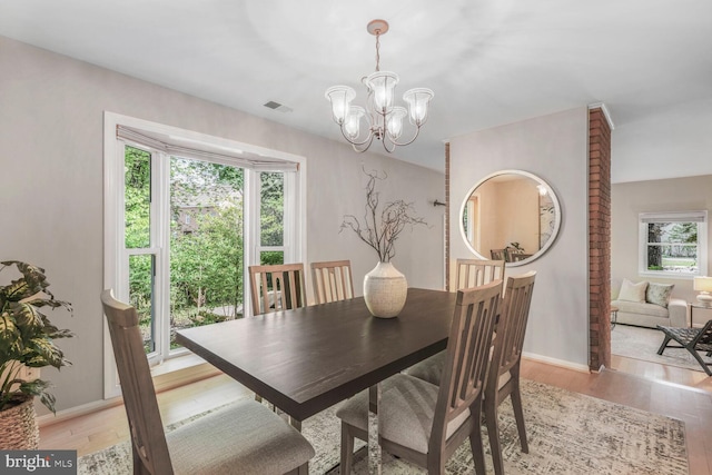 dining room with a chandelier, light wood-style flooring, and baseboards