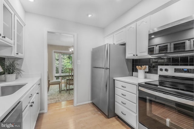 kitchen with stainless steel appliances, white cabinetry, light wood-type flooring, light countertops, and recessed lighting