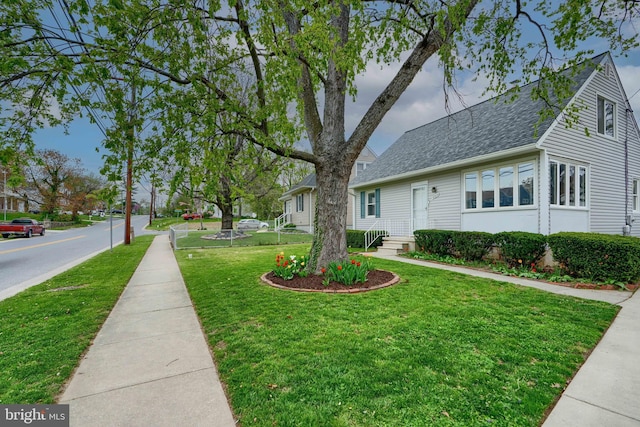 exterior space featuring roof with shingles and a front lawn