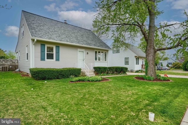 new england style home featuring roof with shingles, central AC, and a front yard