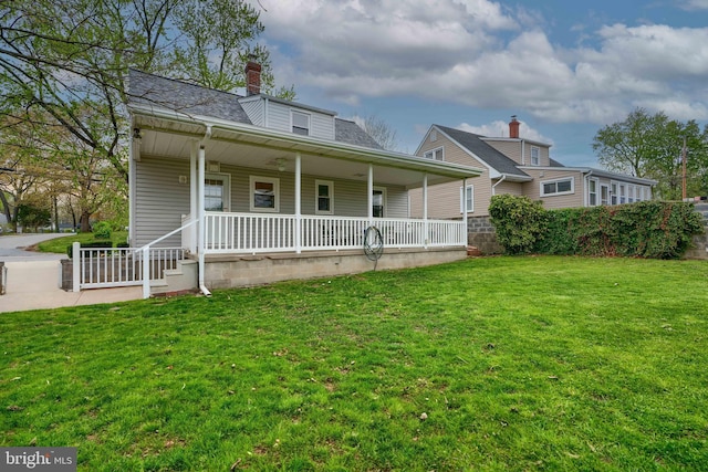 view of front of property with a shingled roof, a chimney, a porch, and a front lawn