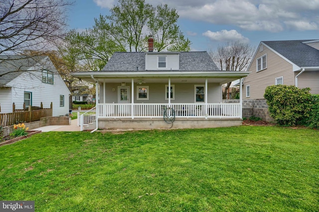 view of front facade featuring a porch, fence, a chimney, and a front yard