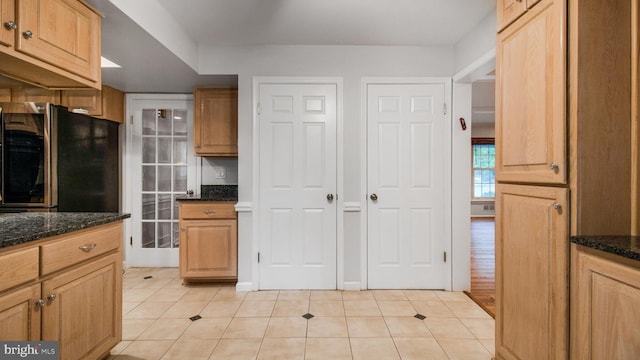 kitchen with smart refrigerator, light tile patterned floors, and dark stone counters