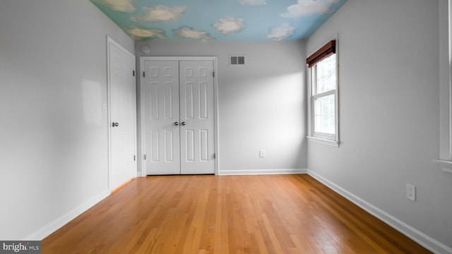 unfurnished bedroom featuring baseboards, light wood-style floors, and a closet