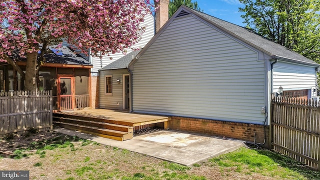 back of property with fence, a wooden deck, and a chimney