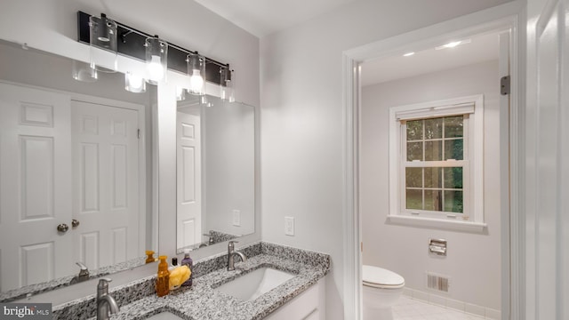 bathroom with toilet, double vanity, and baseboards