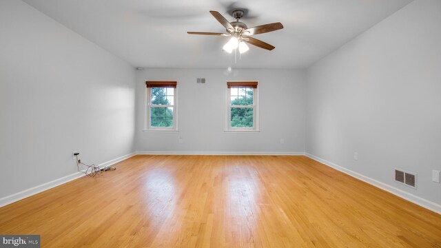 spare room with ceiling fan, light wood-type flooring, and baseboards