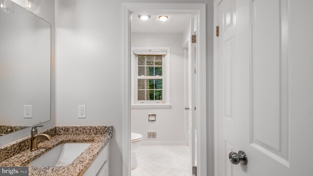 bathroom with toilet, vanity, baseboards, and tile patterned flooring
