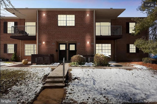 view of front of property with brick siding and a balcony