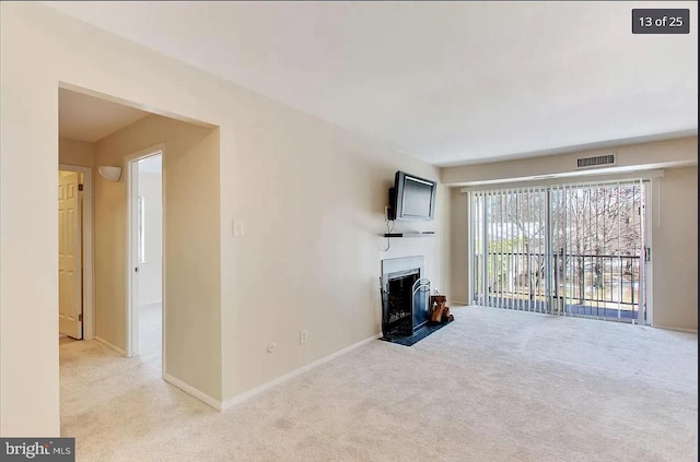 unfurnished living room featuring baseboards, a fireplace, carpet flooring, and visible vents