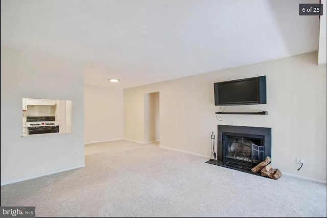 unfurnished living room featuring carpet flooring, baseboards, and a fireplace with flush hearth