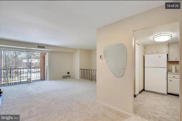 spare room with visible vents, baseboards, and light colored carpet