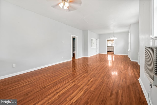 unfurnished living room featuring a ceiling fan, a chandelier, wood finished floors, and baseboards
