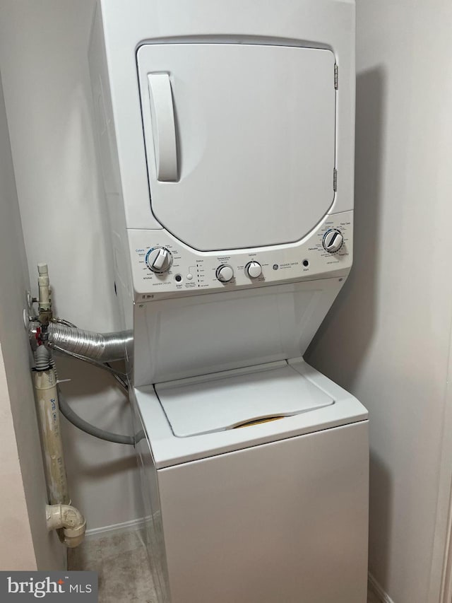 clothes washing area featuring stacked washer and dryer, laundry area, and baseboards