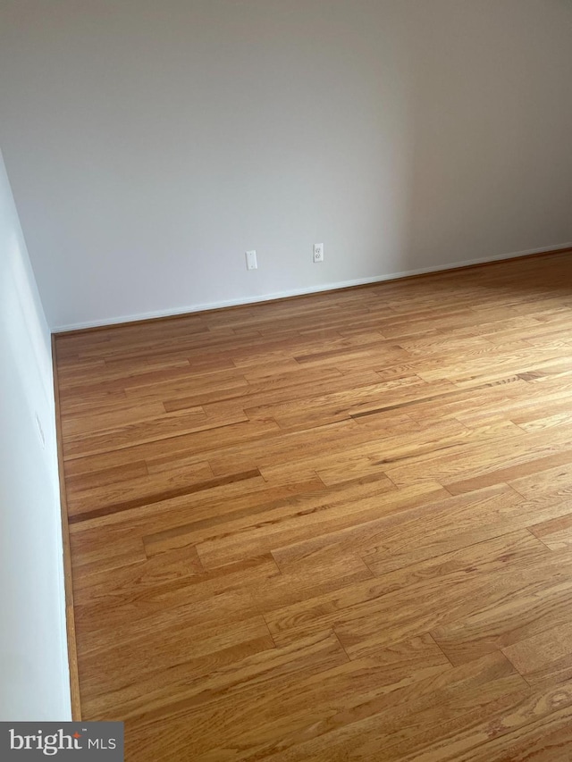 unfurnished room with baseboards and light wood-style flooring