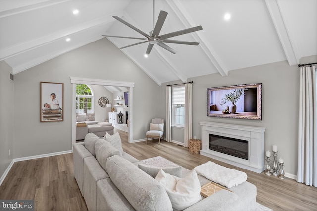 living room featuring a ceiling fan, a glass covered fireplace, and wood finished floors