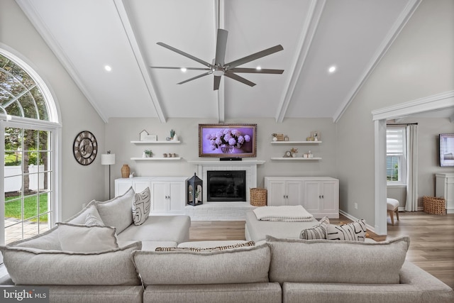 living room featuring ceiling fan, beam ceiling, plenty of natural light, and wood finished floors