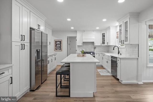 kitchen with decorative backsplash, stainless steel appliances, a sink, and white cabinetry