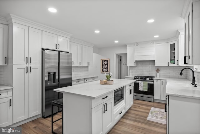 kitchen featuring a kitchen island, a sink, stainless steel appliances, decorative backsplash, and premium range hood