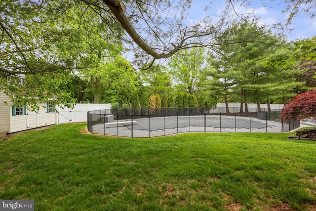 view of yard with fence and a tennis court
