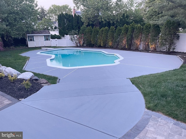 view of swimming pool featuring a storage shed, a patio, an outbuilding, a fenced backyard, and a fenced in pool