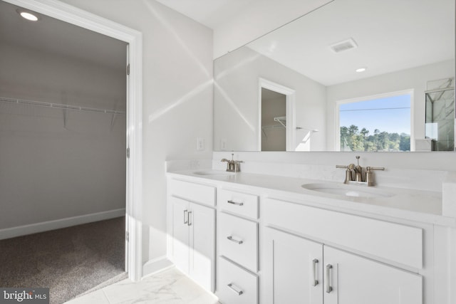 full bath featuring double vanity, a walk in closet, recessed lighting, and a sink