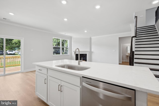 kitchen featuring stainless steel dishwasher, crown molding, a sink, and a kitchen island with sink