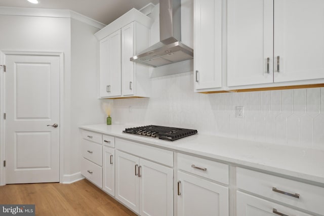 kitchen with wall chimney range hood, white cabinets, decorative backsplash, and stainless steel gas stovetop
