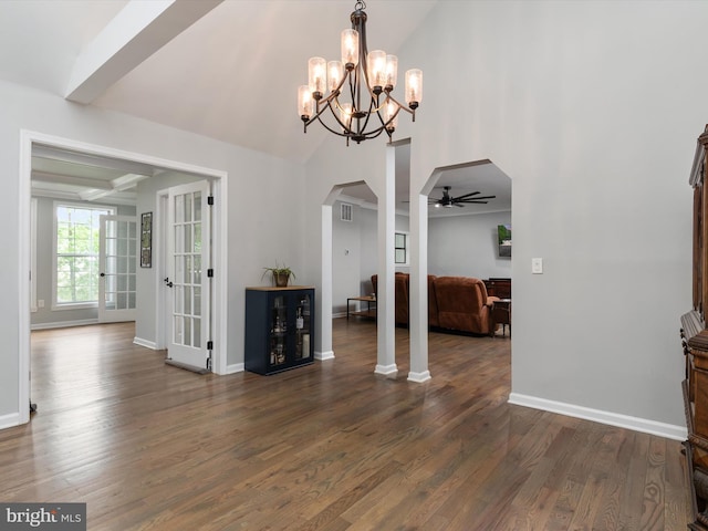 unfurnished dining area featuring arched walkways, ceiling fan, dark wood-style flooring, baseboards, and a chandelier
