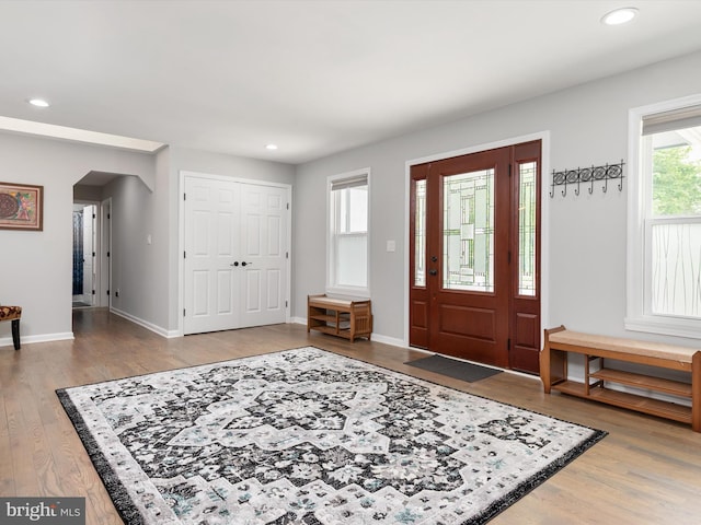 entryway with wood finished floors, recessed lighting, baseboards, and arched walkways
