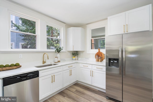 kitchen with a sink, appliances with stainless steel finishes, plenty of natural light, and white cabinets