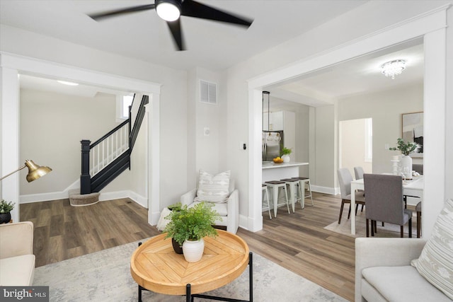 living area featuring stairway, a ceiling fan, wood finished floors, and visible vents