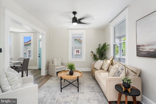 living room with a ceiling fan, baseboards, and wood finished floors