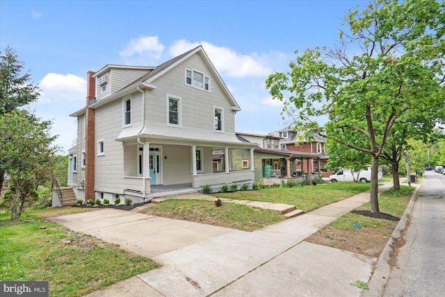 view of front of house with a chimney, covered porch, and a front yard