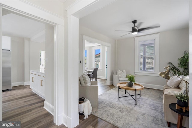 living room featuring baseboards, ceiling fan, a healthy amount of sunlight, and wood finished floors