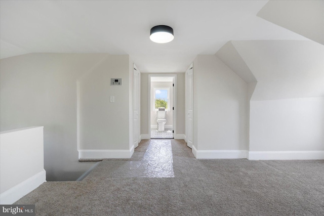 additional living space with carpet floors, baseboards, and vaulted ceiling
