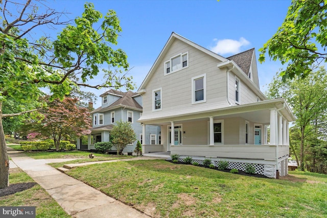 view of front of property with a front lawn, roof with shingles, and covered porch