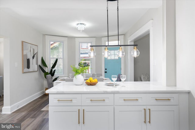 kitchen with dark wood-style flooring, pendant lighting, light stone countertops, baseboards, and white cabinets