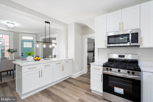 kitchen with light wood finished floors, stainless steel appliances, baseboards, white cabinetry, and a peninsula