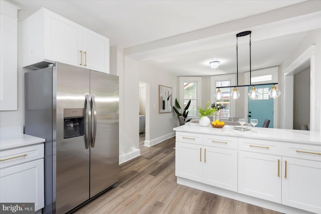 kitchen with white cabinets, hanging light fixtures, stainless steel fridge with ice dispenser, light wood-style floors, and baseboards