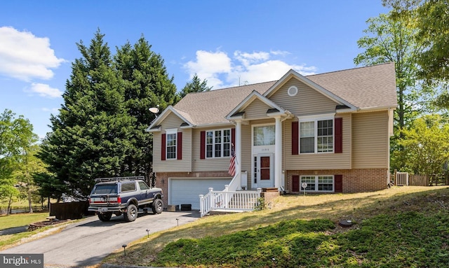 11312 Rawhide Rd, Lusby, MD 20657 - bi-level home with brick siding, a garage, roof with shingles, and concrete driveway