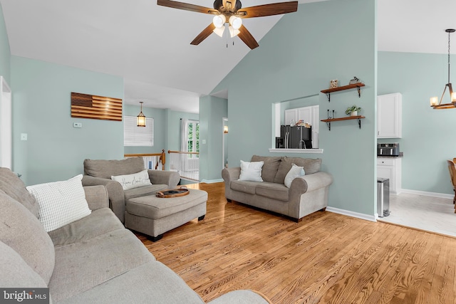 11312 Rawhide Rd, Lusby, MD 20657 - living room featuring high vaulted ceiling, baseboards, ceiling fan with notable chandelier, and light wood finished floors
