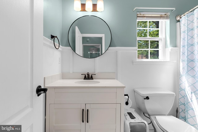 11312 Rawhide Rd, Lusby, MD 20657 - bathroom featuring a decorative wall, toilet, a wainscoted wall, and vanity