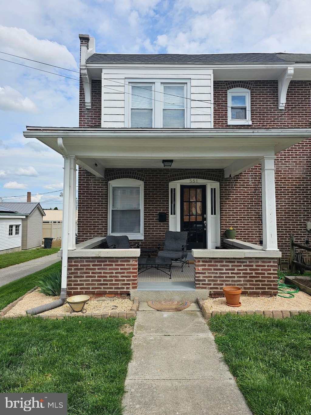 view of front of property featuring a porch, brick siding, and a chimney