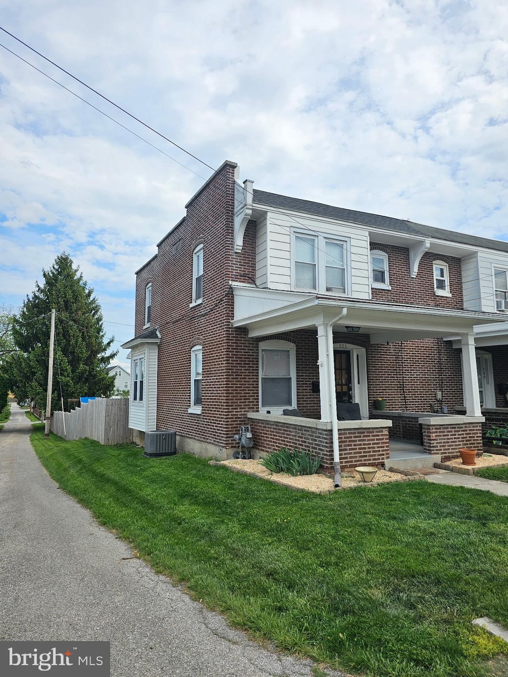 view of front of property with fence, cooling unit, a front lawn, and brick siding