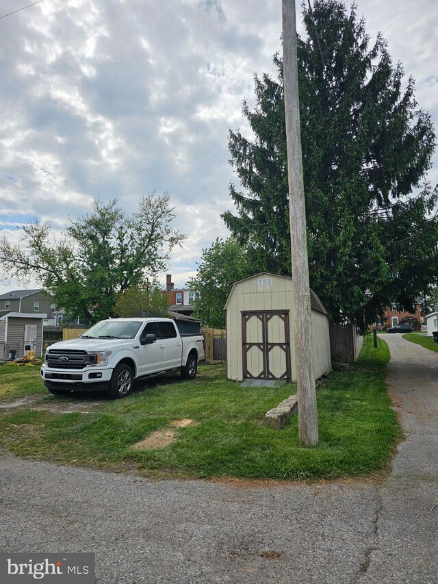 view of vehicle parking with fence and a storage unit